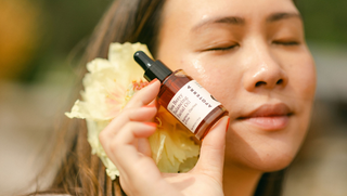 Woman holding Apoterra Sea Berry Facial Oil up to her face