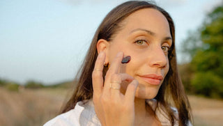woman puts Hibiscus Mud on her cheek in a field