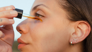 woman putting facial oil on her face outdoors