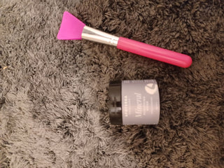 Pink face mask applicator and jar of Mineral face mask on rug.