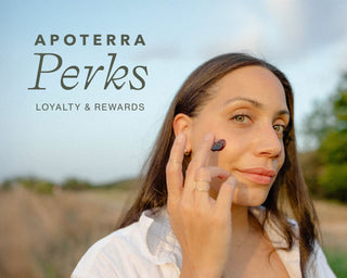 Woman applying Hibiscus Mud to her face outdoors with 'Apoterra Perks' text overlay