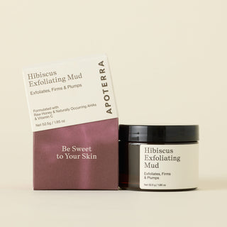 Apoterra Hibiscus Exfoliating Mud jar next to its product box on a warm cream background. The jar has a black lid and a white label, while the box is white on top and a deep plum-brown on the bottom with the text 'Be Sweet to Your Skin'.