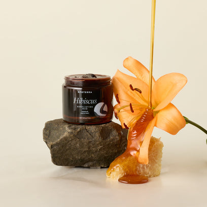 Jar of Apoterra's Hibiscus Exfoliating Mud Mask with a flower and honey drizzle lifestyle photo