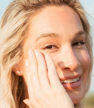 Close up image of a women applying Apoterra's Sea Berry Balancing Facial Oil to her face.