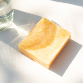Pumpkin Wild Carrot Complexion Soap by Apoterra lifestyle photo showing the soap bar sitting in a light-filled space highlighting the Apoterra logo embossed on the soap bar.