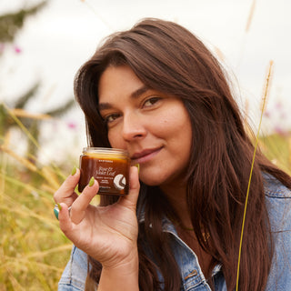 Woman holding a jar of Apoterra Rose & Violet Leaf Body Butter outside