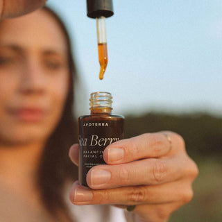 Sea Berry Balancing Facial Oil held by model using dropper for application 
