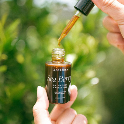 A drop of Sea Berry Balancing Facial Oil Dripping from Dropper in an outdoor lifestyle photo