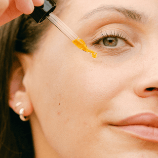 Close up of a woman applying Sea Berry Balancing Oil to her cheek