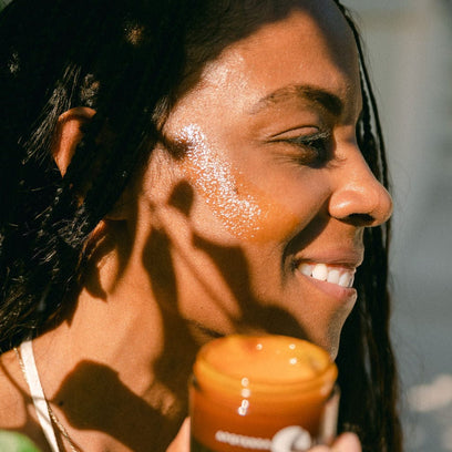 Apoterra's Vitamin C balm face application by model on cheek for glowing skin