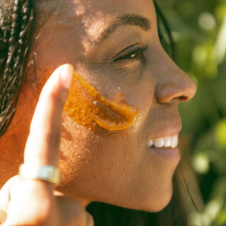 Woman applies Apoterra's Vitamin C Balm to face for glowing skin